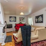 Wohnzimmer mit Sofa, Sessel, Kamin und Wandbildern