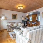 Wohn- und Essbereich mit zwei Sofas, Holzdecke und Tisch mit Stühlen.