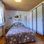 Schlafzimmer mit Bett, Kleiderschrank und Fenster mit Blick auf die Natur.