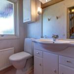 Badezimmer mit Toilette, Waschbecken und Fenster mit getöntem Glas.
