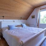 Schlafzimmer mit Doppelbett, Holzdecke und Balkonansicht.