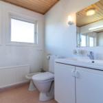 Badezimmer mit Waschbecken, Toilette und Bidet. Holzdecke und zwei Fenster.