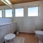 Badezimmer mit Toilette, Bidet und Waschbecken. Drei Fenster und Holzdecke.