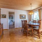 Esszimmer mit Holztisch, Stühlen und Sideboard. Holzdecke und Parkettboden.