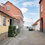 Kurze Straße mit roten Ziegeldächern und Steinmauern führt zum Hafen.