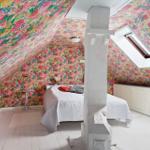 Schlafzimmer mit floraler Tapete, Dachfenster und weißem Boden.