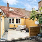 Hinterhof mit Terrasse, Sitzgelegenheit und Baum mit Laternen.