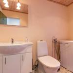 Badezimmer mit Waschmaschine, Toilette und Waschbecken unter Spiegel.