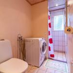 Badezimmer mit Toilette, Waschmaschine und Dusche mit Blumenvorhang.