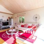 Wohnzimmer mit weißem Sofa, rotem Teppich und Holzdecke.
