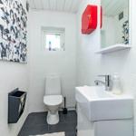 Badezimmer mit Toilette, Waschbecken und Wandbild mit Porträts.