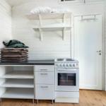 Küche mit Kochfeld, Schrank und Regal. Tür und Wand mit Bildern.