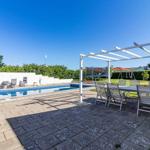 Poolbereich mit Sitzgelegenheiten und Pavillon. Hintergrund mit Grün und Haus.