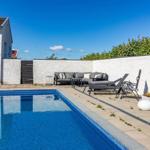 Poolbereich mit Loungemöbeln und weißen Wänden unter blauem Himmel.