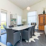 Essbereich mit Esstisch, Stühlen und Wohnbereich mit Sofa und Holzschrank.