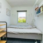 Schlafzimmer mit Bett, Fenster, Wandregalen und Schreibtisch.