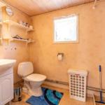 Badezimmer mit Toilette, Waschbecken und Dusche. Fenster, Regal und Teppich sind sichtbar.
