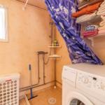 Badezimmer mit Dusche, Waschmaschine und Regalen für Handtücher.