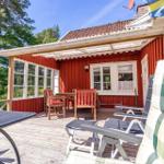 Roter Holzhaus mit Terrasse, Gartenmöbel und Blick in den Wald.