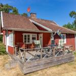 Rotes Holzhaus mit Terrasse, Garten und schwedischer Flagge.