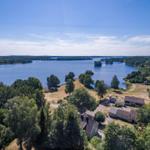 Haus am See mit Wald und Inseln im Hintergrund.