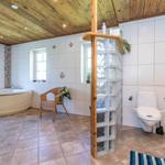 Badezimmer mit Badewanne, Toilette und Glasblockwand