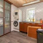 Wohnung mit Waschmaschine, Spüle und Fenster. Holzdecke und Schrank mit Glasfront.