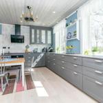 Küche mit grauen Schränken, Essbereich und großem Fenster. Holzboden und Deckenleuchte.