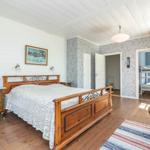 Haupt Schlafzimmer mit Holzbett, Tapete und Blick in Nebenraum mit Schlafcouch.