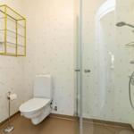 Badezimmer mit Dusche, WC und Waschbecken mit goldfarbenen Akzenten.
