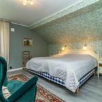 Schlafzimmer mit Bett, Nachttisch, Fenster und grünem Sessel.