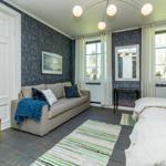 Zimmer mit Sofa, Bett und Fenstern. Wandtapete, Teppich und Decke.