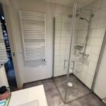 Badezimmer mit Dusche, Handtuchhalter und Waschbecken