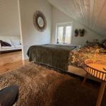 Schlafzimmer mit Bett, Teppich und Sitzgelegenheit. Holzboden und Dachschrägen.