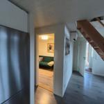 Küche mit Kühlschrank, Flur mit Holztreppe und Blick in Wohnzimmer mit Sofa.
