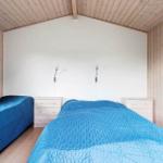 Zwei Betten mit blauen Bettdecken, Nachttische und Wandlampen in einem Holzhauszimmer.