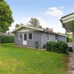 Ein graues Haus mit Garten und Flagge. Neben einem kleinen Schuppen.