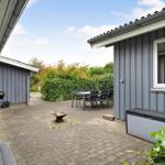Terrasse mit Grill, Sitzgruppe und Feuerkorb. Umgeben von grüner Vegetation.