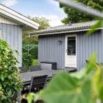 Haus mit Terrasse, Tisch und Stühlen. Umgeben von Grün und Pflanzen.