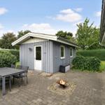 Hinterhof mit Grillplatz, Tisch und Stühlen. Kleines Haus mit Fenstern und Tür.