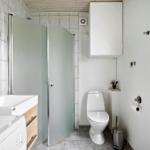 Badezimmer mit Dusche, Waschbecken und Toilette. Fenster und Spiegel sorgen für Tageslicht.