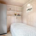 Schlafzimmer mit Holzwand, Bett, Kleiderschrank und Wandbild mit Fisch.