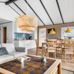 Wohn- und Essbereich mit Küchenzeile, Holztisch, Sofa und Deckenleuchte.