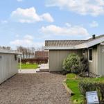 Haus mit Holzfassade, Garten und Terrasse unter blauem Himmel.