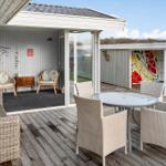 Terrasse mit Sitzgruppe und Tisch. Hintergrund: Wohnbereich mit Stühlen und Wanddekoration.