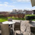 Terrasse mit Tisch und Stühlen, Blick auf Rasen und Hecke.