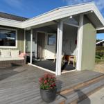 Terrasse mit Sitzgelegenheit und Blick ins Haus. Pflanze und Holzdielen.
