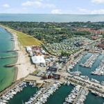 Aerielansicht eines Hafens mit Booten, Strand und Campingplatz.