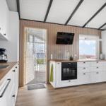 Küche mit Holzplatten, weißen Schränken und Blick auf den Hof.