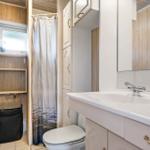 Badezimmer mit Waschbecken, Toilette und Dusche mit Vorhang.